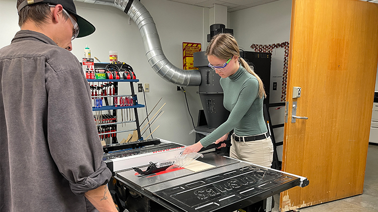 Student using a table saw with instructor supervising