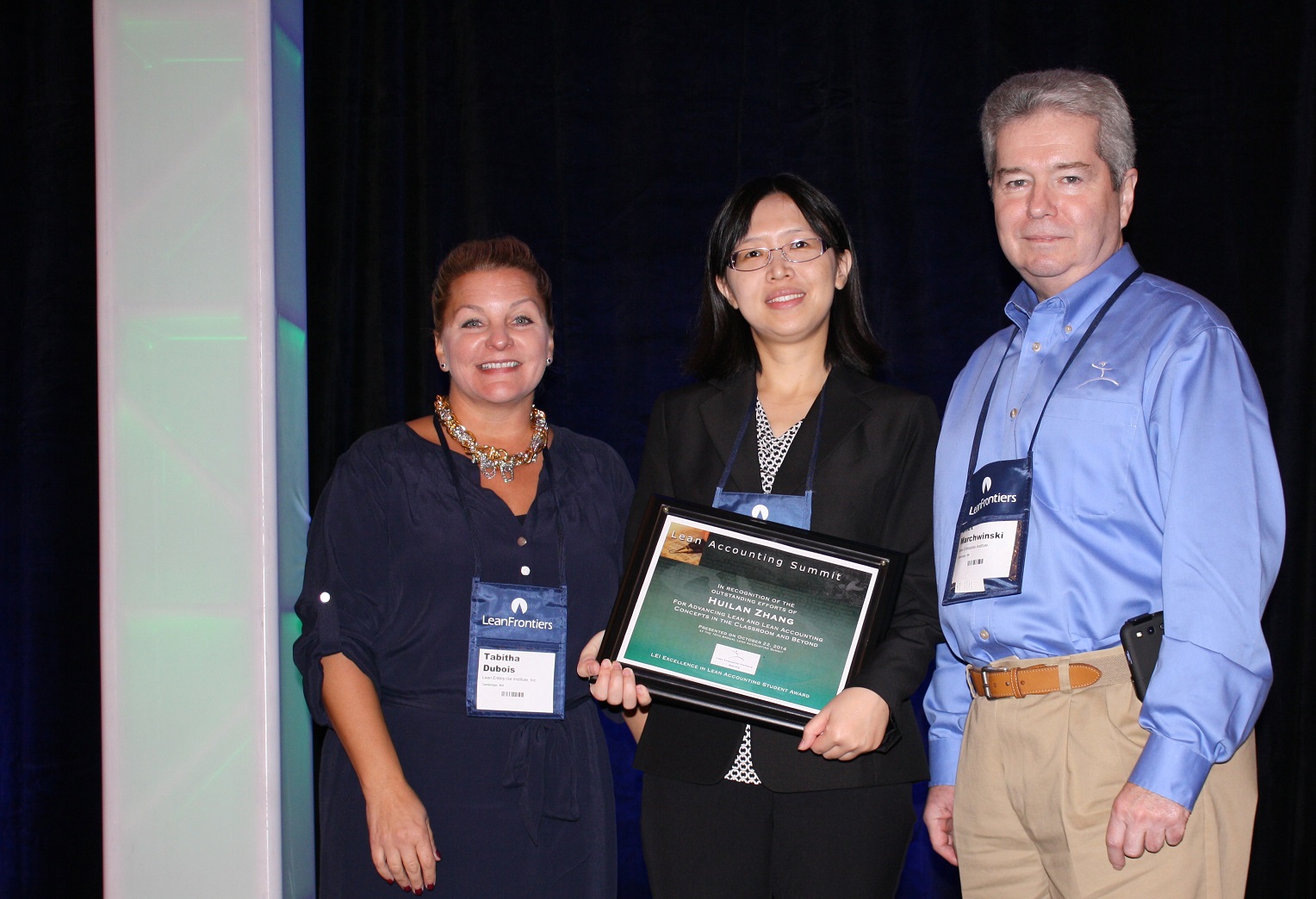 Student Huilan Zhang, center, accepts her 2014 Excellence in Lean Accounting Award from Chet Marchwinski and Tabitha Dubois of the Lean Enterprise Institute