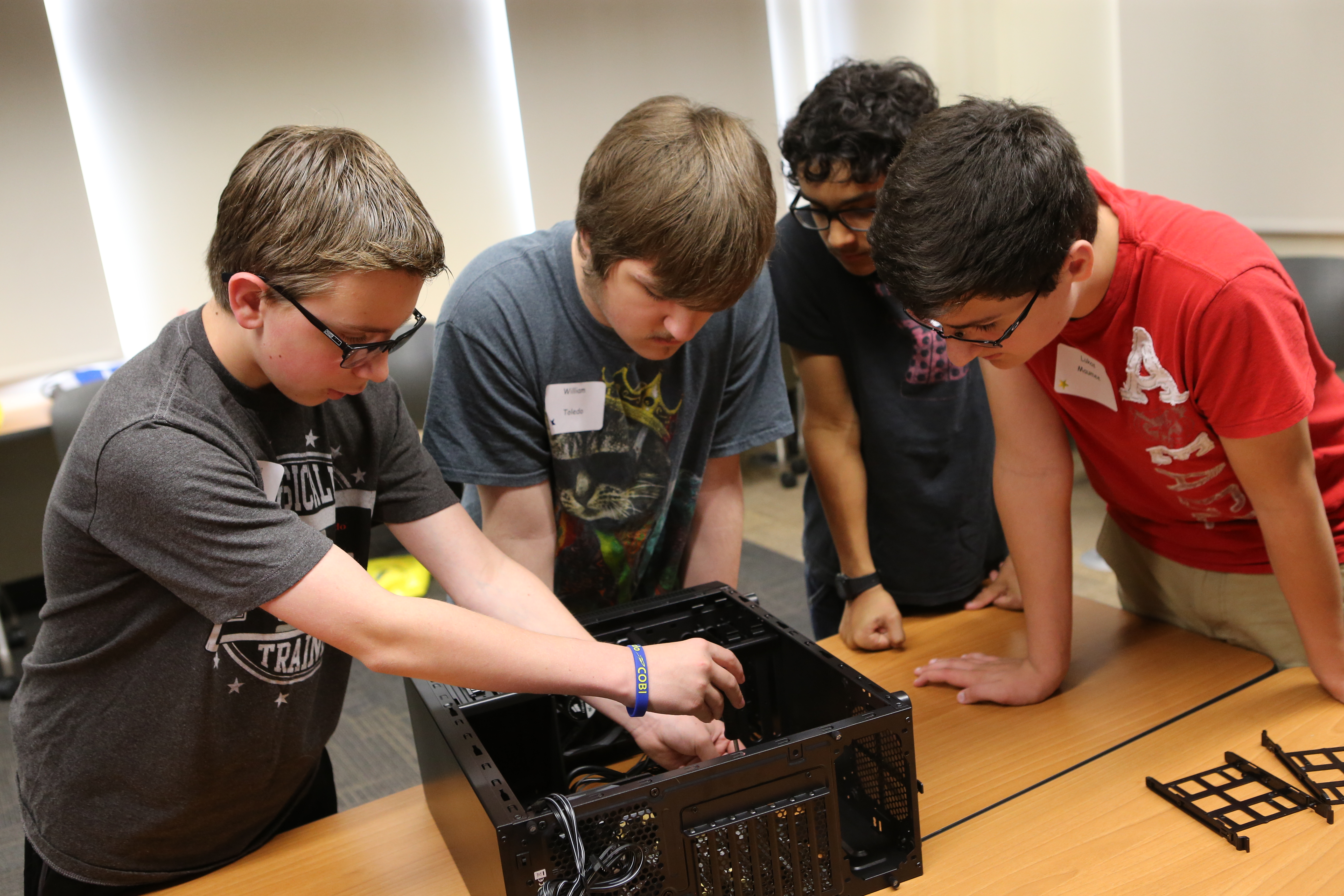 A tech camp student fastens down a motherboard