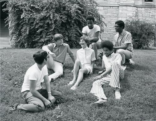 A group of students from the 60s chatting outside.