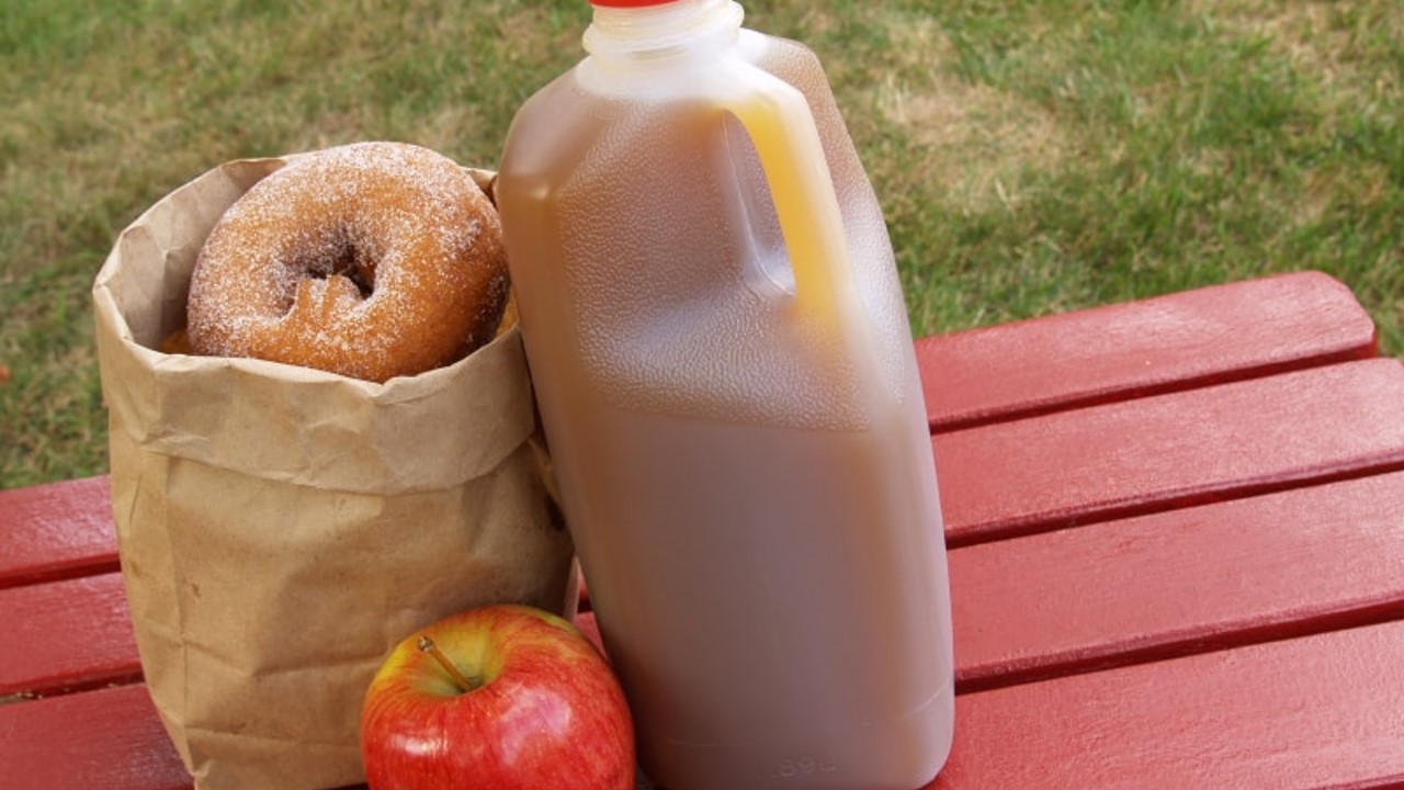 Image of a bag of donuts and cider on a table