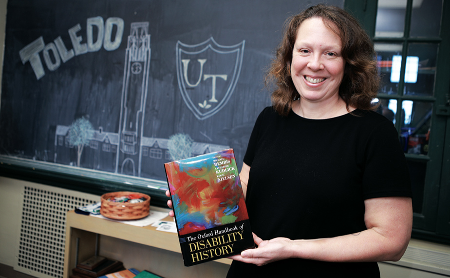 Dr. Kim Nielsen posing with 'The Oxford Handbook of Disability History'
