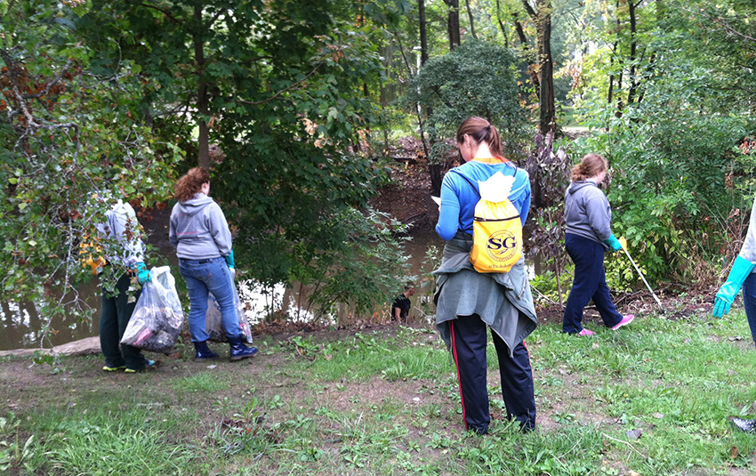 UToledo students and faculty removing trash from the bank of a stream.