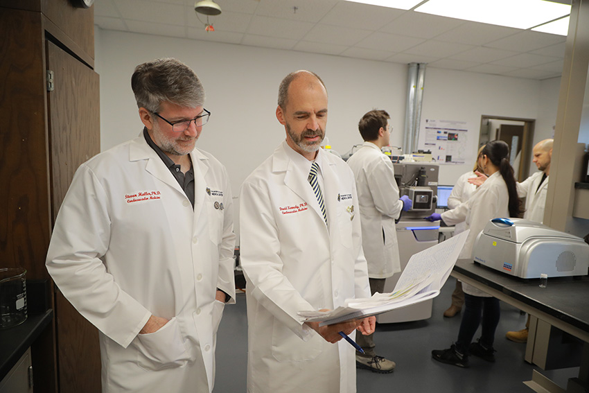David Kennedy, Ph.D. and Steven Haller, Ph.D. looking over documents in a laboratory setting