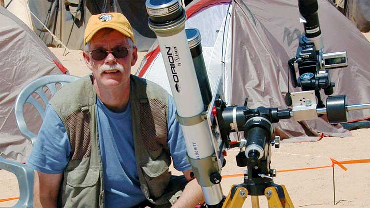 Photo of UT alumnus Fred Espenak next to a telescope