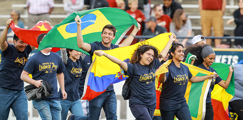 International students running with flags on football field