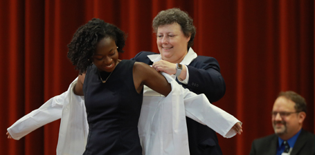 A student receiving her white coat