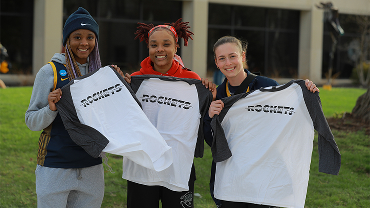three students showing off rocket shirts