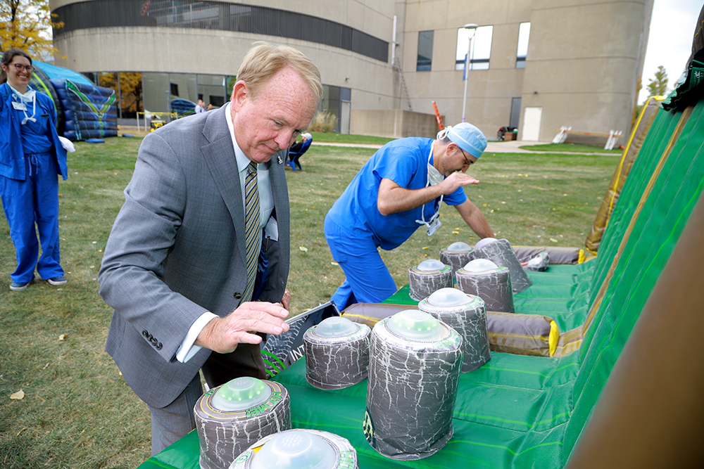 Dr. Postel plays a game with a student in scrubs on the Health Science Campus during the Founder's Day BBQ