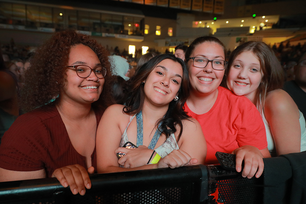 A group of four women smiling at the camera during the concert