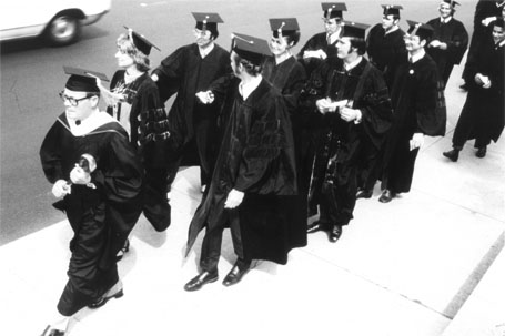 A group of graduates in caps and gowns walking on campus
