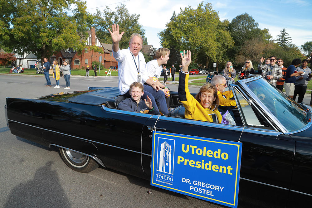 Dr. Postel, president of The University of Toledo, rides in a vintage car with his family during the Homecoming Parade and waves at spectators
