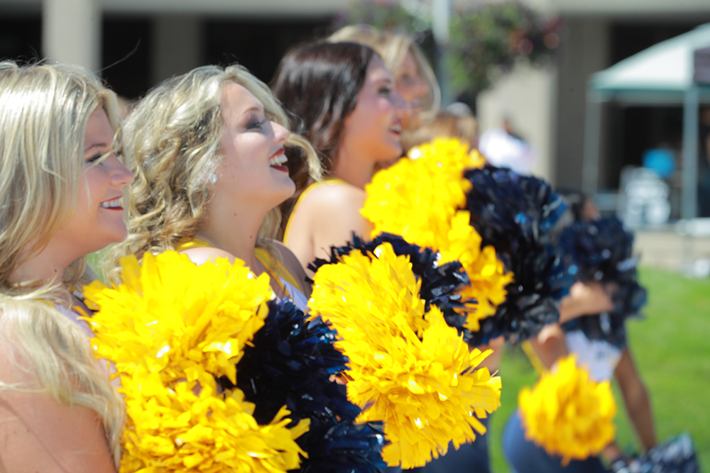UToledo cheerleaders hold their pom poms up while cheering at the pep rally