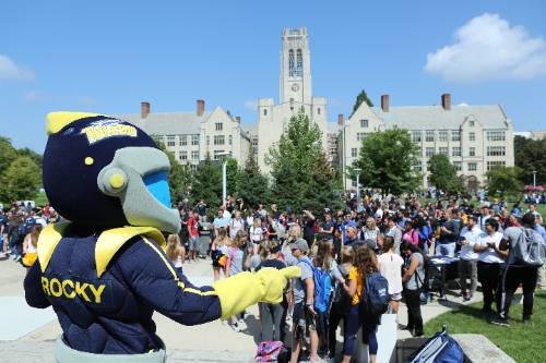 Rocky the mascot looking out to a crowd of students on campus