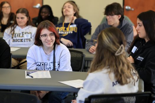 students in UToledo gear gathered around the table