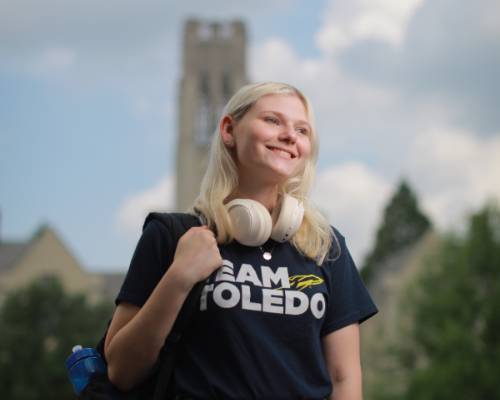 student smiling in front of the bell tower