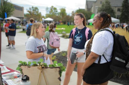 Three students talking to each other at a campus event