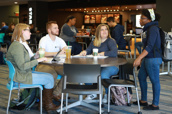 Students talking around a table near Starbucks in Carlson Library
