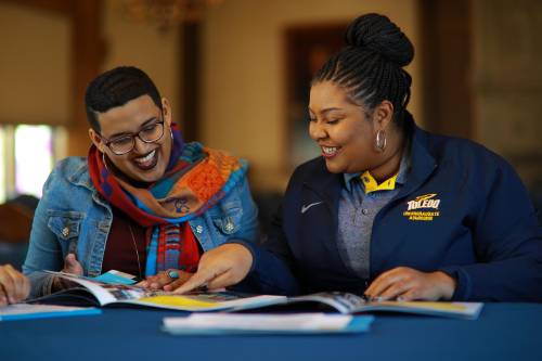 student talking with admission counselor at a table looking at a brochure