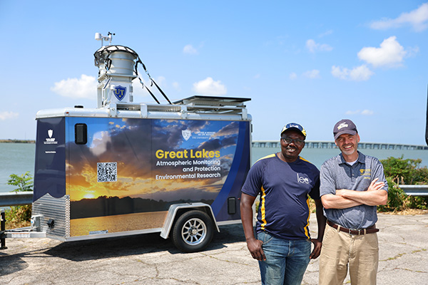 Two people outside of a research trailer