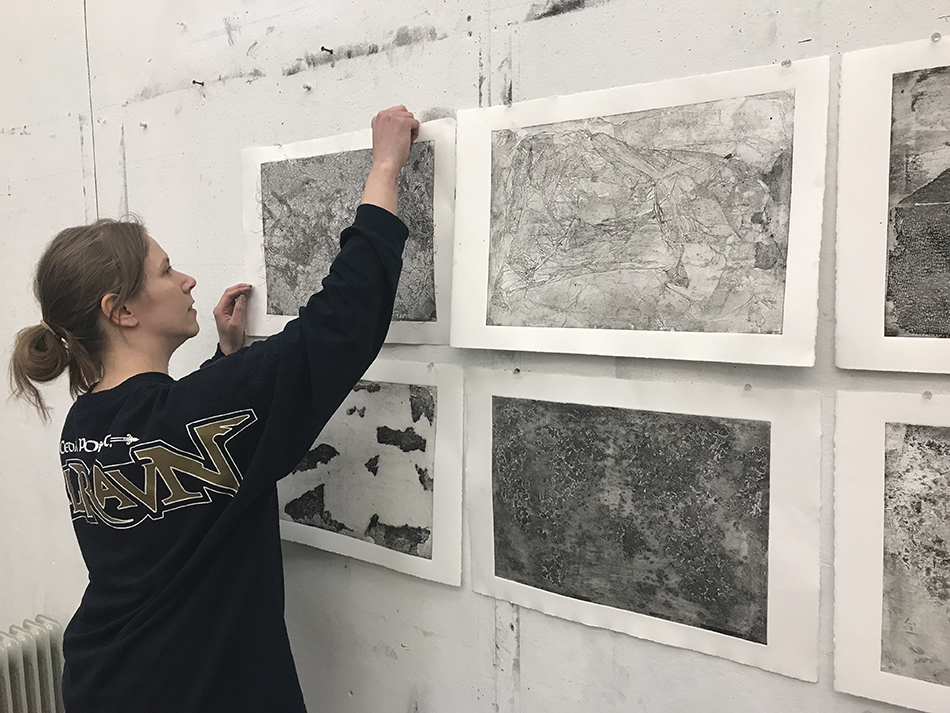 student pinning artwork to wall