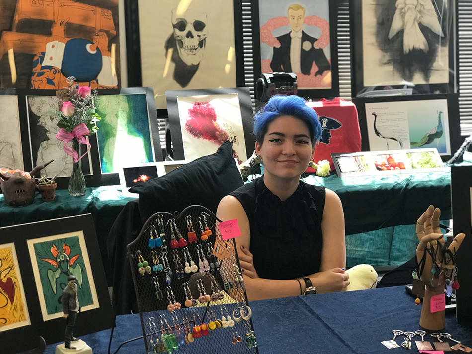 Art student seated with various artwork pieces around 