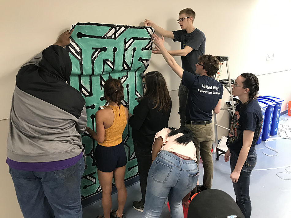 Students attaching a paper mural in the UT Incubator Research unit.