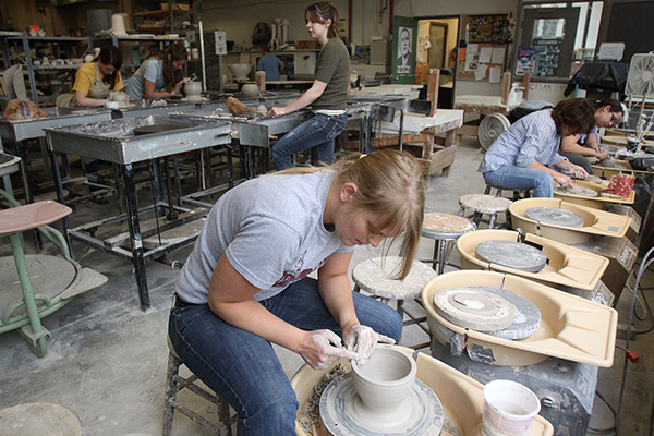 Students workin on a ceramics wheel at the Center for the Visual Arts
