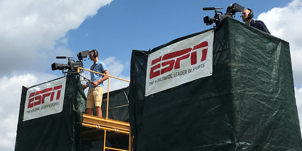 Student camera operator atop a scaffolding stand shooting a golf tournament for ESPN