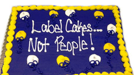 Photo of a blue and gold cake that reads Label Cakes Not People