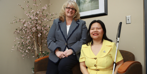 Photo of two women, one is blind and holds a walking cane