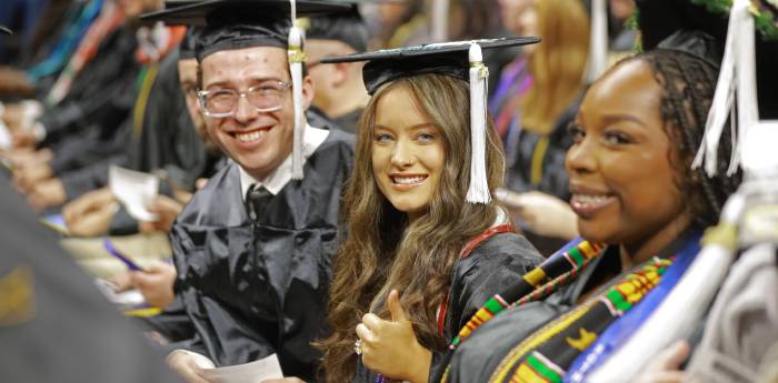 A trio of UToledo graduates seated at the commencement ceremony