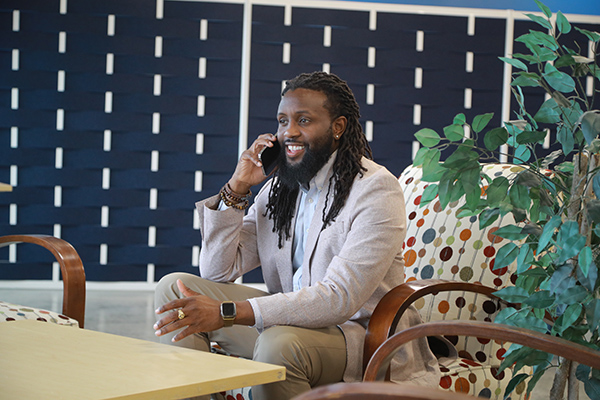 a man wearing business professional clothing sitting in a chair talking on his cell phone