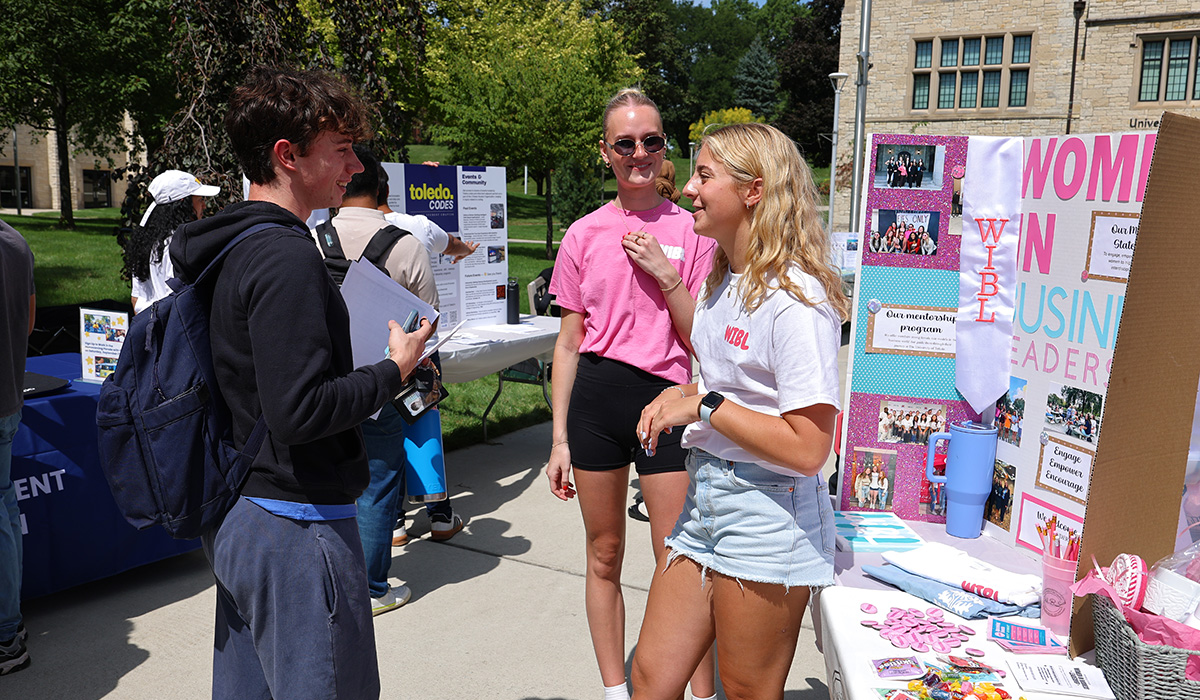 Students at the utoledo student involvement fair in centennial mall. Students are talking to eachother and there are tables set up with information about different student organizations.