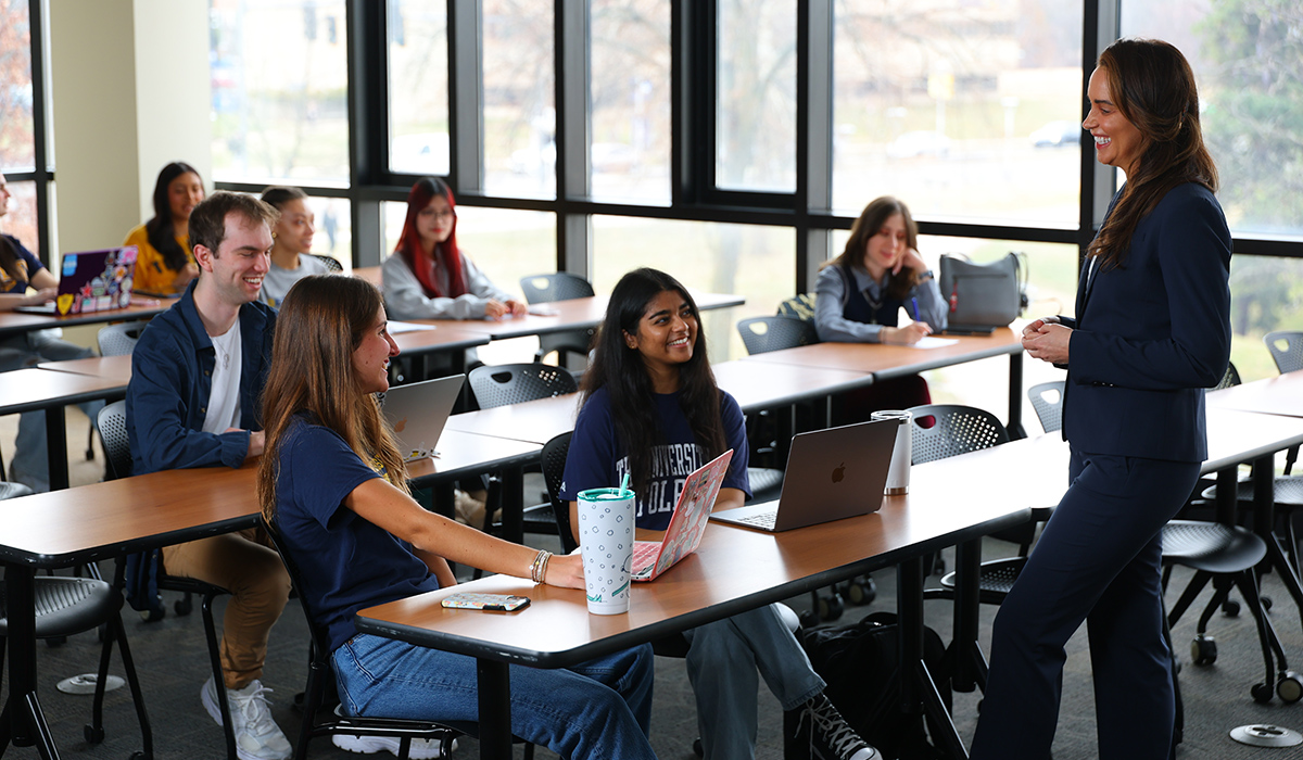 Associate Professor Elizabeth Napier smiling and talking with business students in a classroom during a lecture