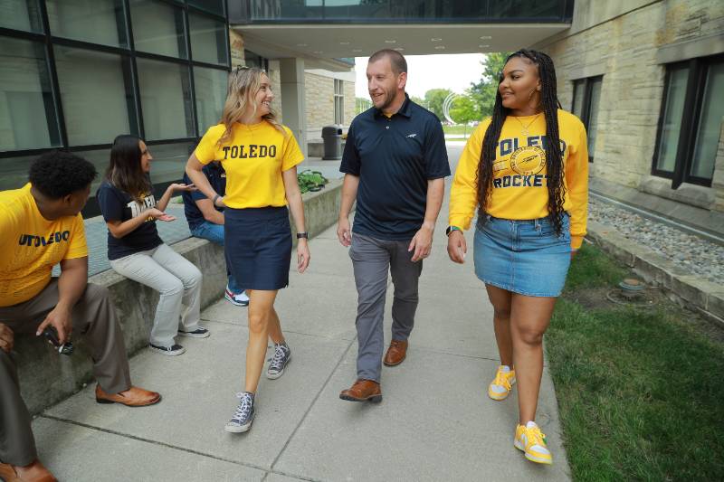 Students walking through campus with UToledo spirit wear on.