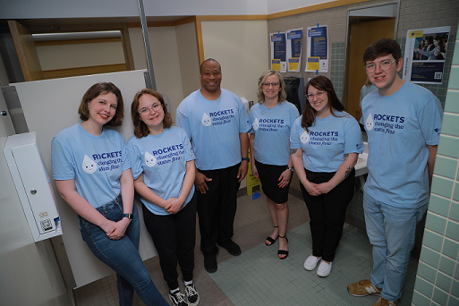 6 people next to a free period product dispenser