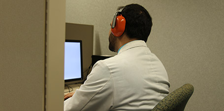 man sitting at a desk with a monitor and headphones on