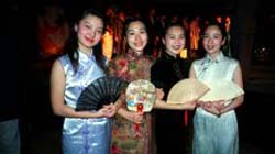 Four women in traditional Asian dresses with fans