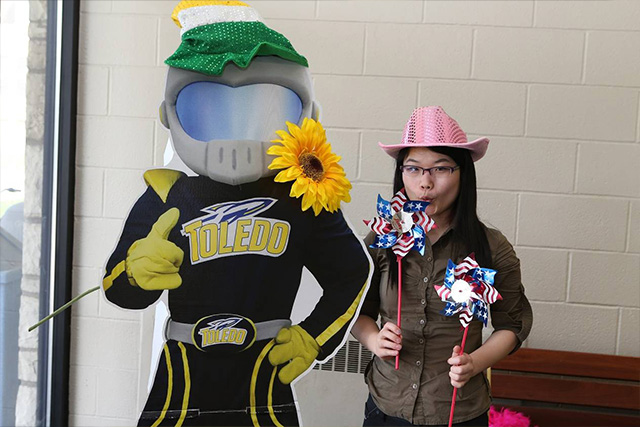 An international student posing with Rocky the mascot