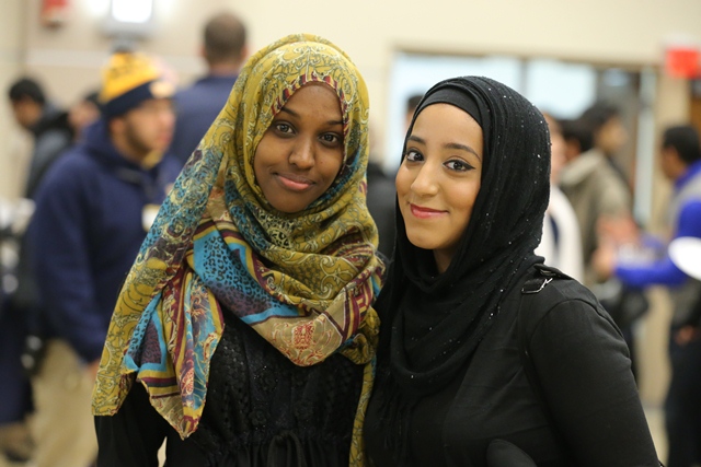 Two international students wearing head scarves standing together and smiling