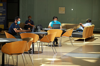 a group of students wear masks and socially distance as they study