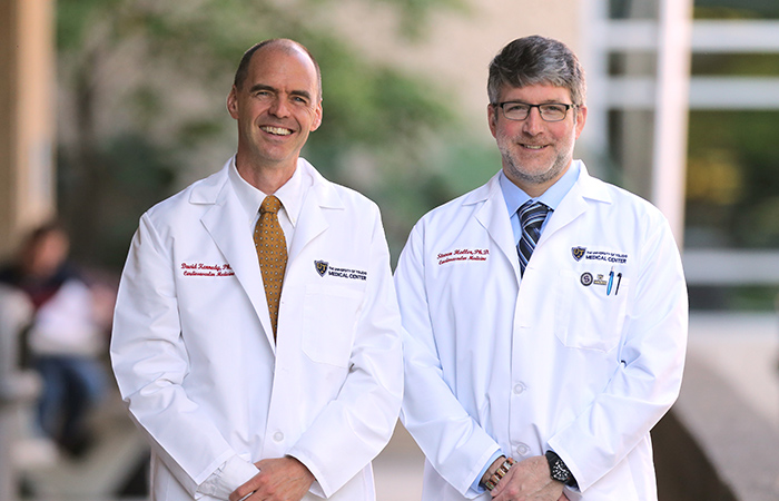 Photo of two faculty members in white coats with the medical center in the background.