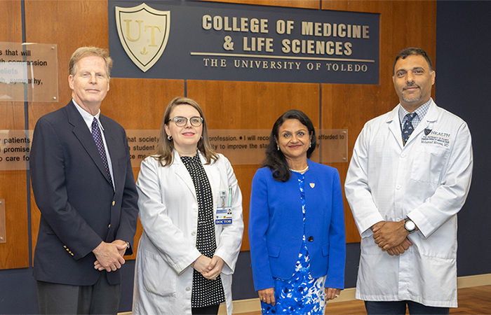 Faculty members pose for a photo in front of the College of Medicine logo