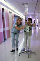 nurse walking in hospital hallway with adolescent patient