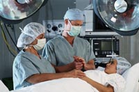 medical staff in gowns and face masks in operating room holding hands with patient 