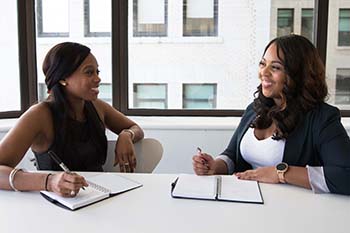 African American business women at a table smiling