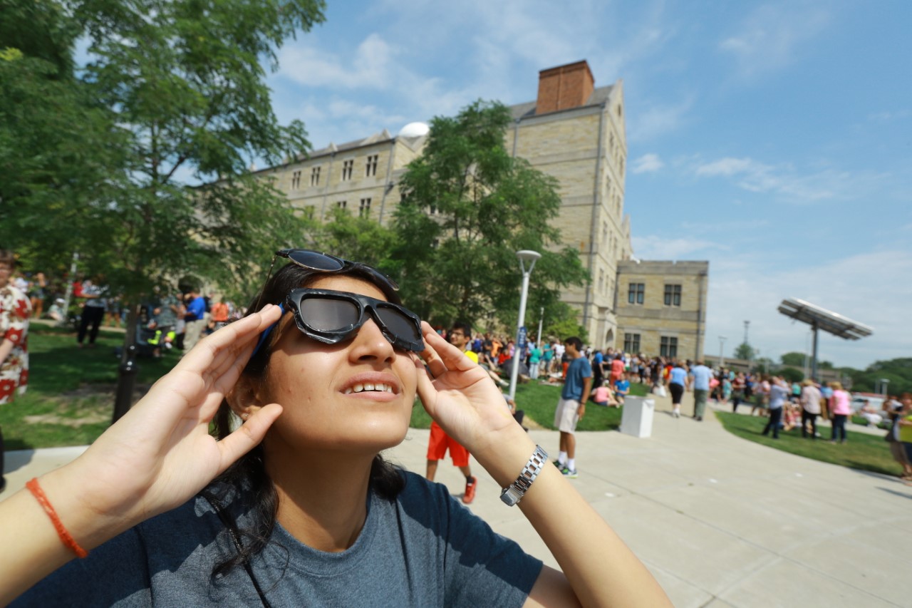 girl looking at sun with eclipse glasses