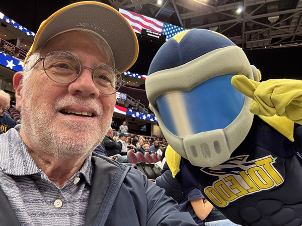 Larry Yonovitz taking a selfy with the UToledo Mascot Rocky inside the Savage arena stadium 