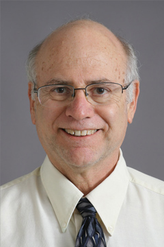 smiling man with glasses in white shirt and blue tie